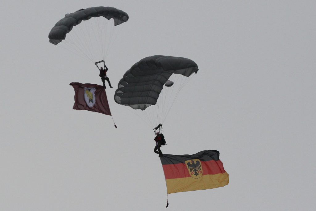 Bild 1: Mit Weihnachtsmütze auf dem Kopf gleiten zwei Fallschirmspringer der Division Schnelle Kräfte mit der Bundesdienstflagge sowie dem Wappen der Division Schnelle Kräfte vom Himmel herab. (Foto: Bundeswehr/Ritter)